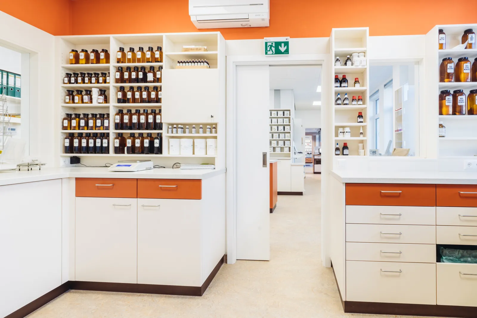 Labor der Christophorus Apotheke mit Standgefäßen aus Braunglas, Waage und weißen Arbeitsflächen