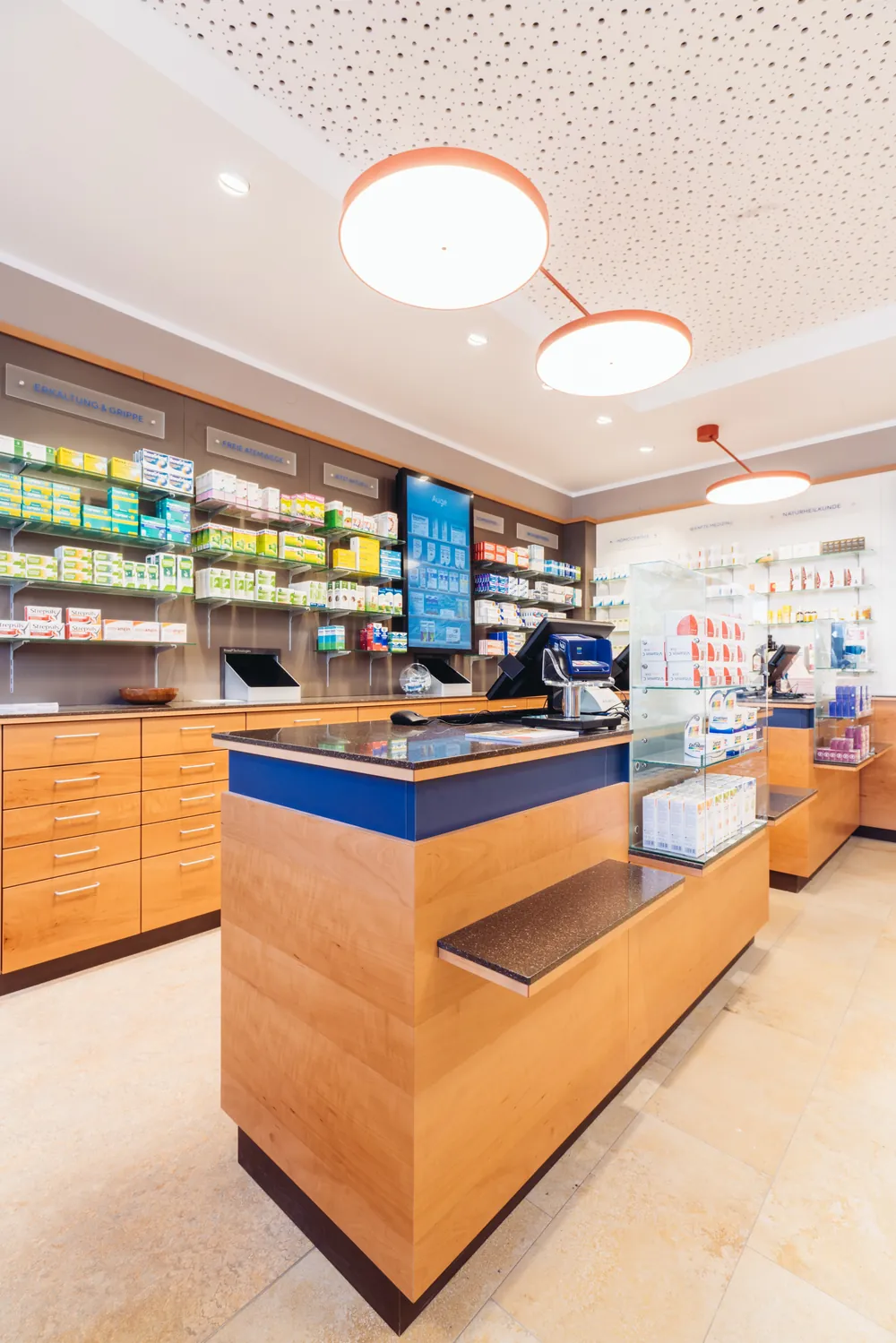 Beratungstisch aus Holz mit blauer Kante in der Christophorus Apotheke, im Hintergrund Regale mit Arzneimitteln